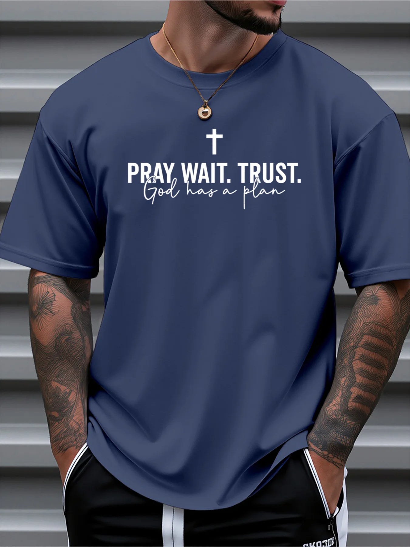 Person wearing a navy blue t-shirt with motivational text and cross symbol.