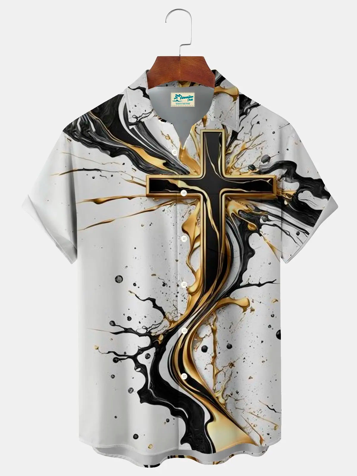A short-sleeve button-up camp shirt with a large black and gold cross graphic on a white background, featuring black and gold paint splatter details, hanging on a wooden hanger against a light gray background.