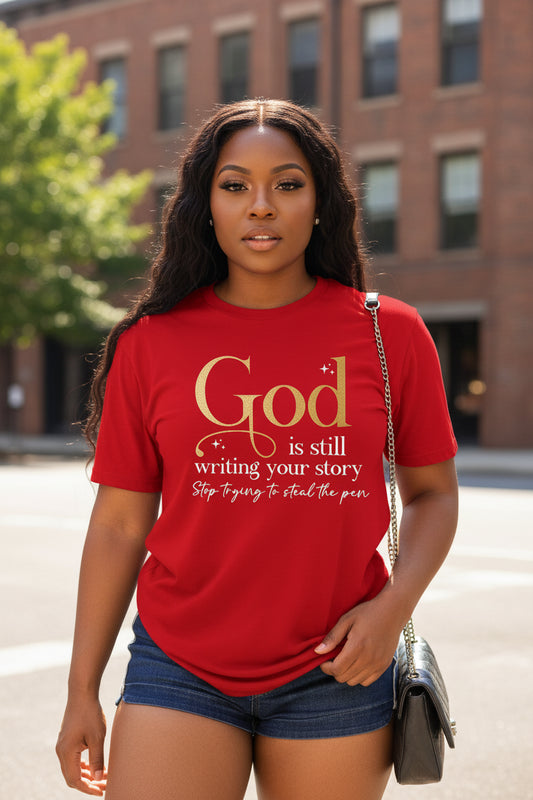 Woman wearing a red Christian graphic T-shirt featuring the message "God Is Still Writing Your Story. Stop Trying to Steal the Pen."