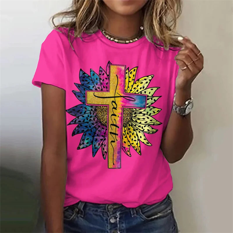 Person wearing a pink t-shirt with a colorful cross and 'faith' design.