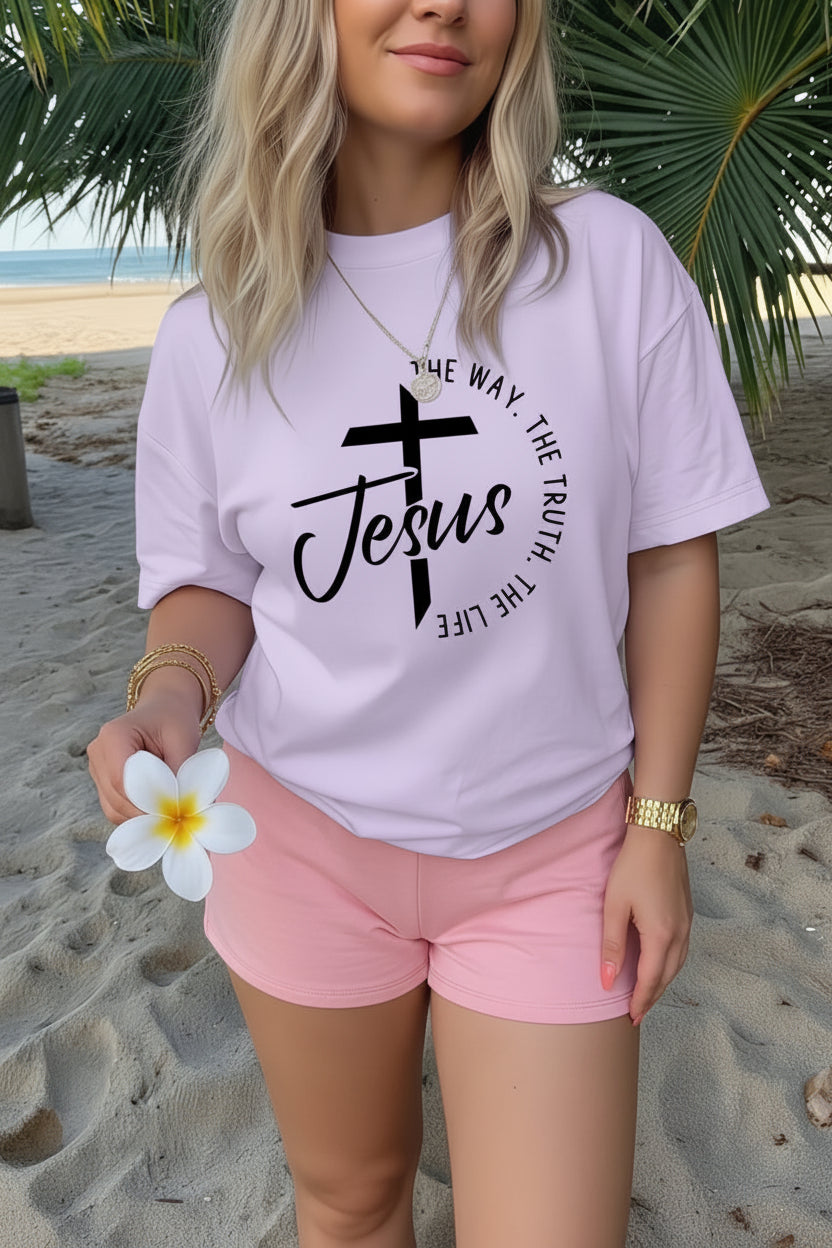 Person wearing a white t-shirt with 'Jesus' and cross design on a beach.