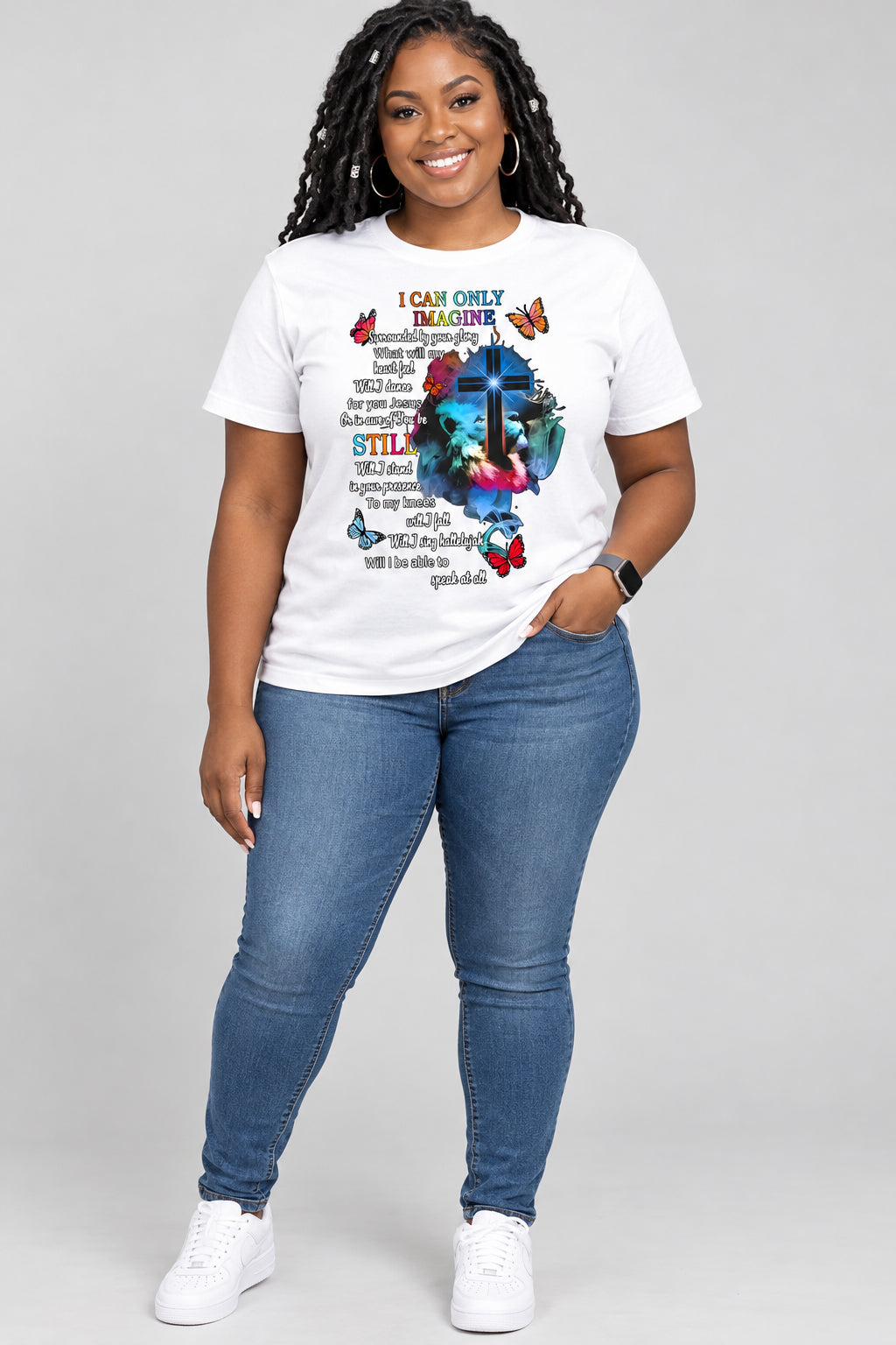 A white sleeveless crop top worn by a model, featuring a colorful graphic with a cross, butterflies, and inspirational text.