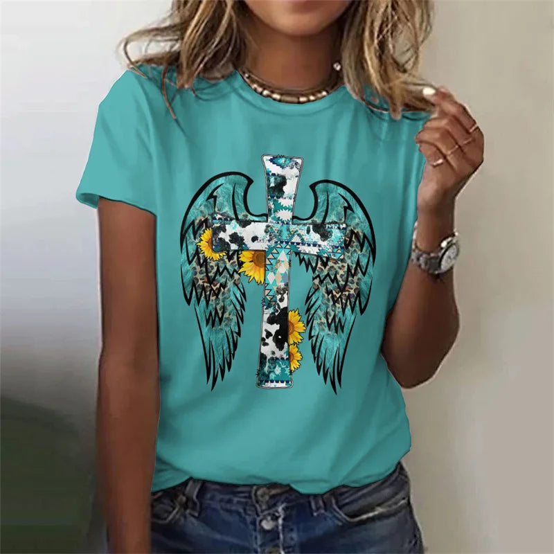 Person wearing a turquoise t-shirt with a graphic design featuring wings and a cross.