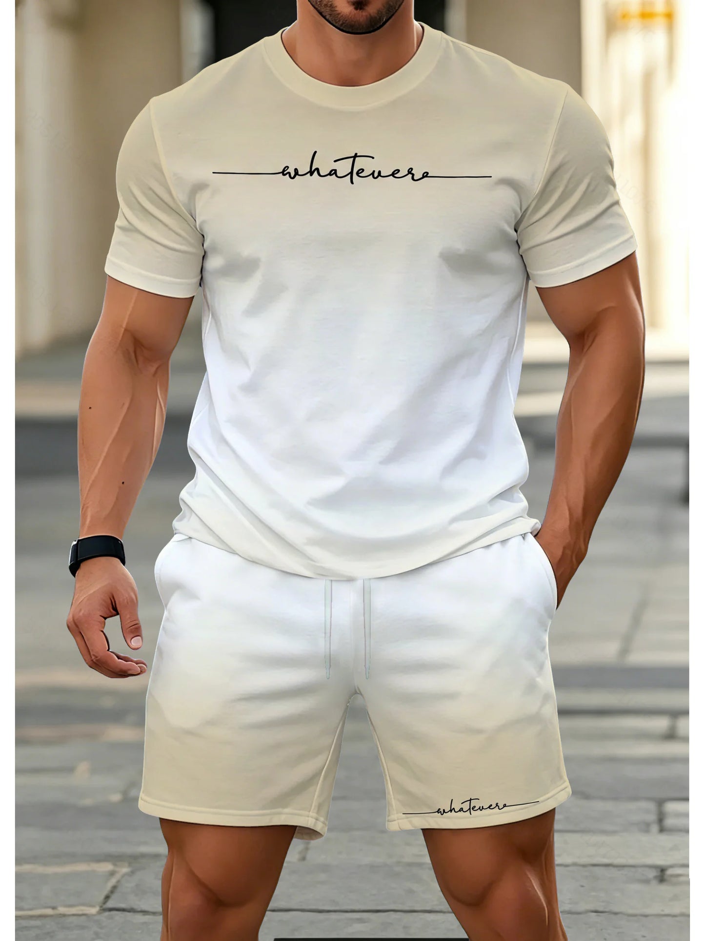 A man wearing a matching beige/cream two-piece lounge set consisting of a short-sleeve crewneck t-shirt and shorts, both featuring the word 'whatevers' printed in black script across the chest and lower leg respectively.