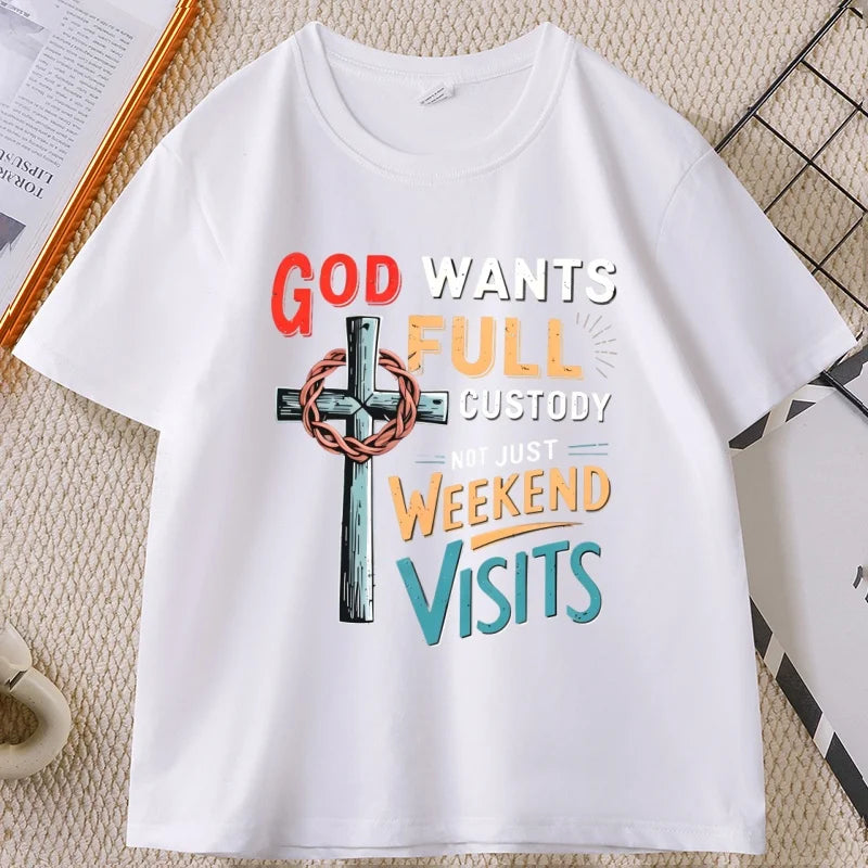 A white short-sleeve crewneck t-shirt with a colorful graphic print on the front. The graphic features a metallic-textured cross with a crown of thorns and the text 'GOD WANTS FULL CUSTODY NOT JUST WEEKEND VISITS' in red, orange, yellow, and blue lettering.
