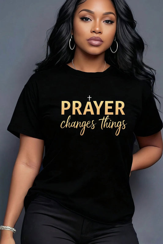 Person wearing a black t-shirt with 'PRAYER changes things' text in gold.