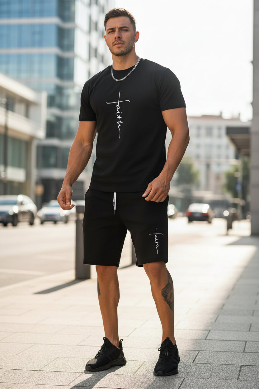 Person wearing a black t-shirt and shorts with 'faith' printed on them, standing on a street.