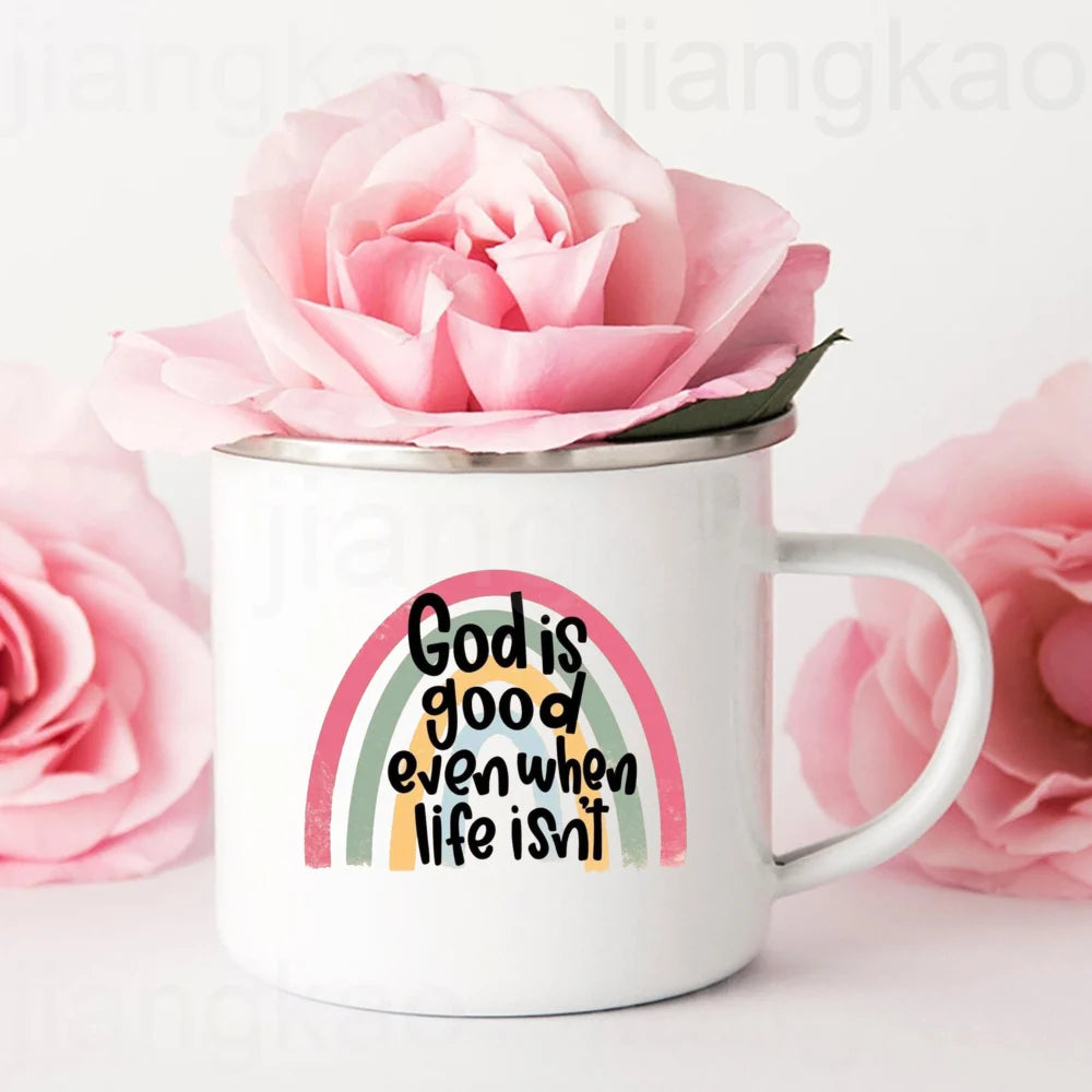 White mug with rainbow and 'God is good even when life isn't' text, surrounded by pink roses.