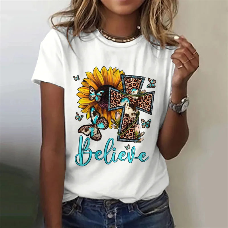 White t-shirt with a sunflower, cross, and butterfly design on a plain background