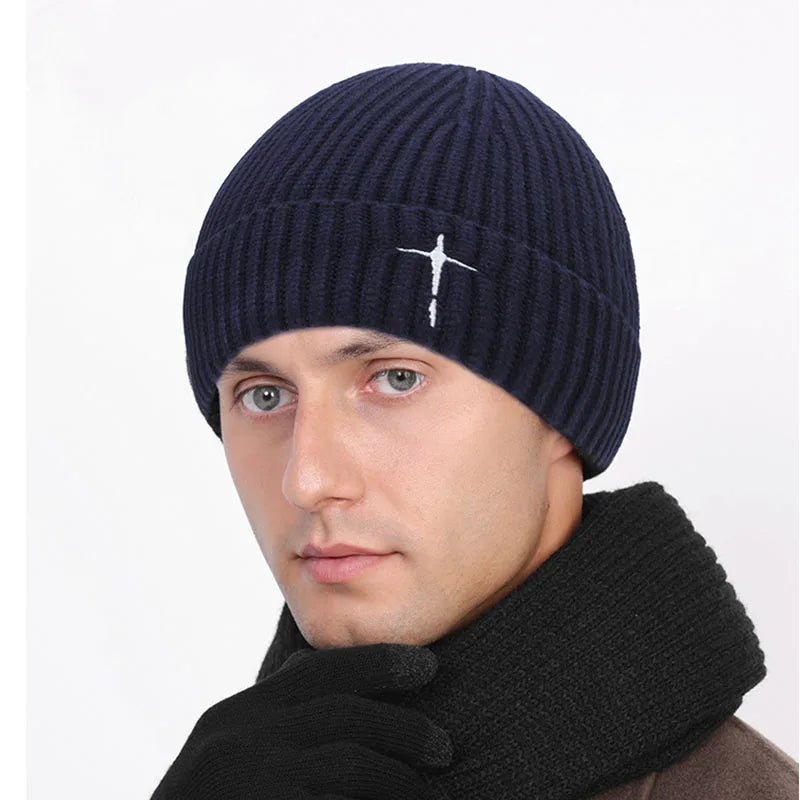 Man wearing a navy blue beanie with a white cross design 